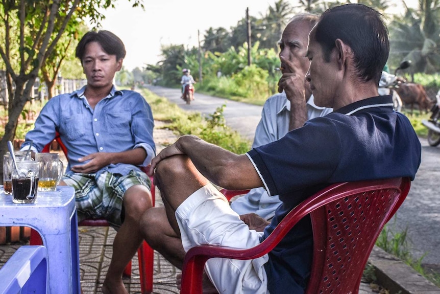 Men sit around a table sharing a cup of tea