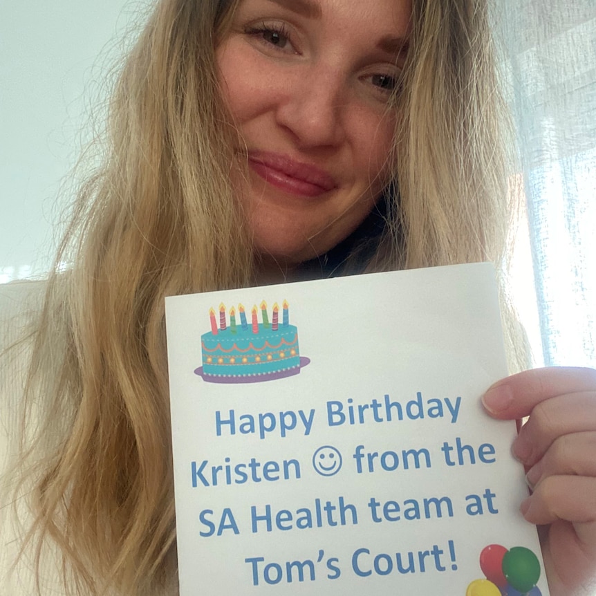 A woman holding a card saying happy birthday