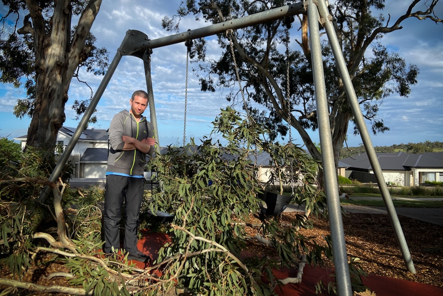 A man with a swing set covered in fallen branches.