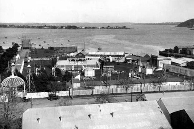 Black and white historical photo of an amusement park on the shores of a river.