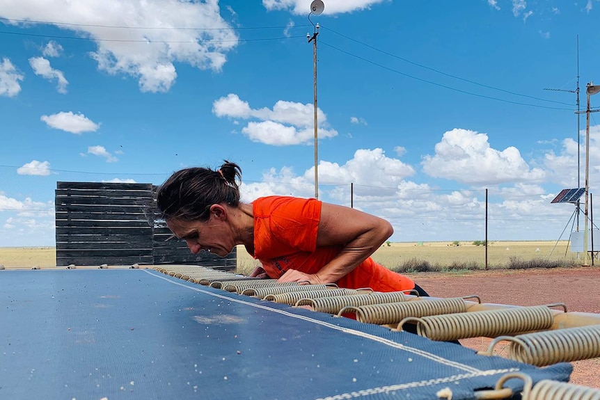 A woman doing push-ups against a trampoline