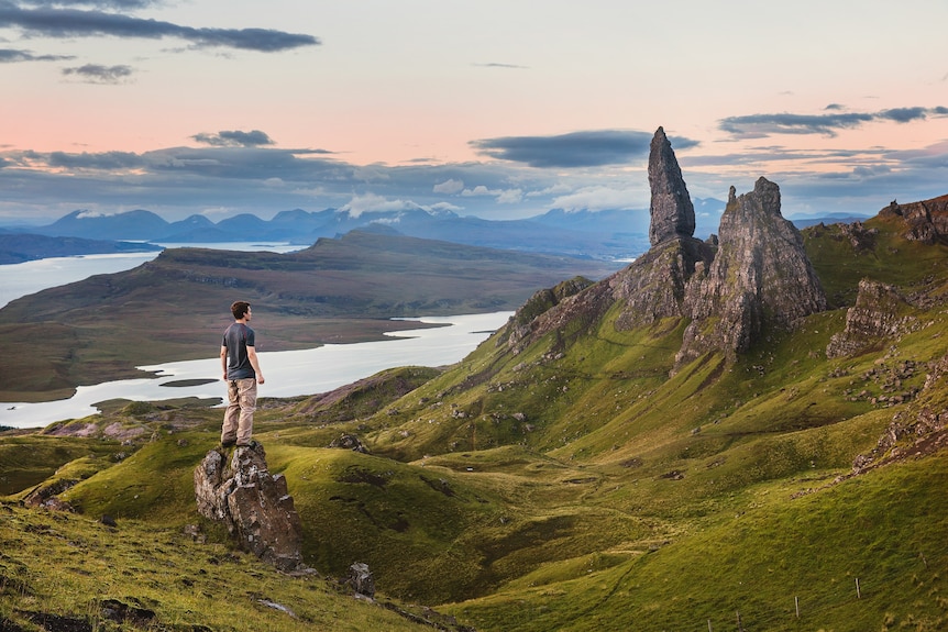 A man standing on a grassy mountain, looking at the view