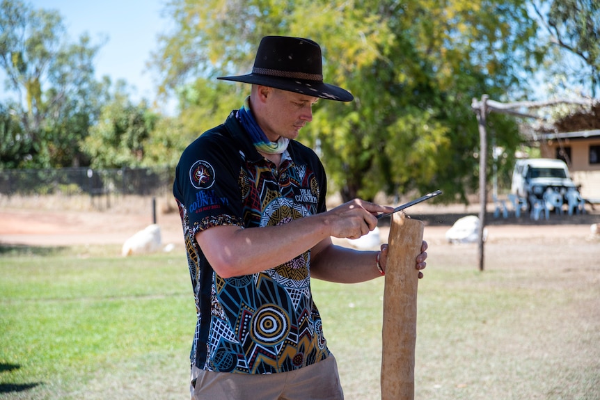 Un homme au chapeau dépose un didgeridoo à Barunga.