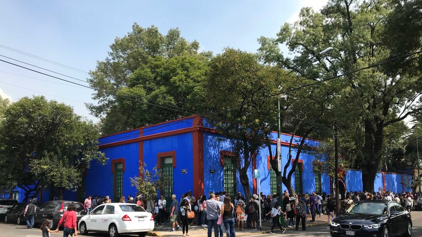 Hundreds of people lining up around the block of a bright blue building - Frida Kahlo's home in Mexico City.