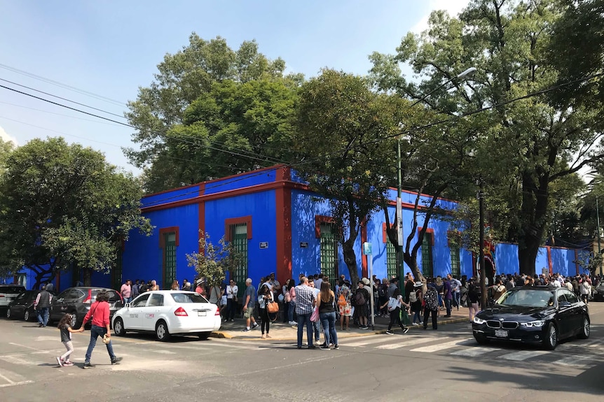 Hundreds of people lining up around the block of a bright blue building - Frida Kahlo's home in Mexico City.