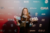 An image of Sycco holding two awards she won at Queensland Music Awards