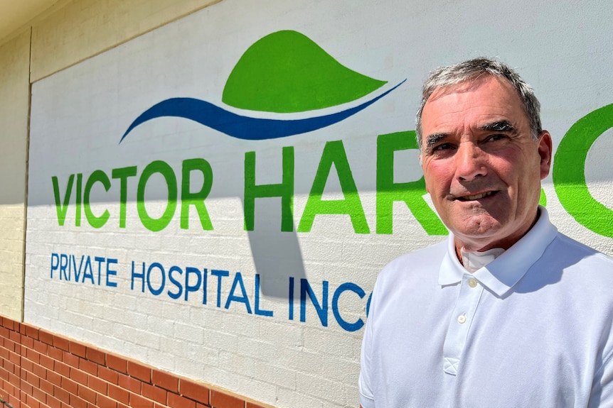 A man stands in front of a sign that reads Victor Harbor Private Hospital