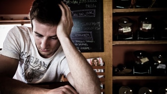 Depressed young man sitting at counter in a cafe (Thinkstock: Photos.com)
