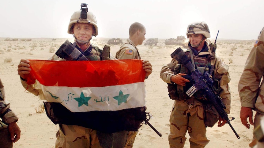 A US soldier shows off a captured Iraqi flag