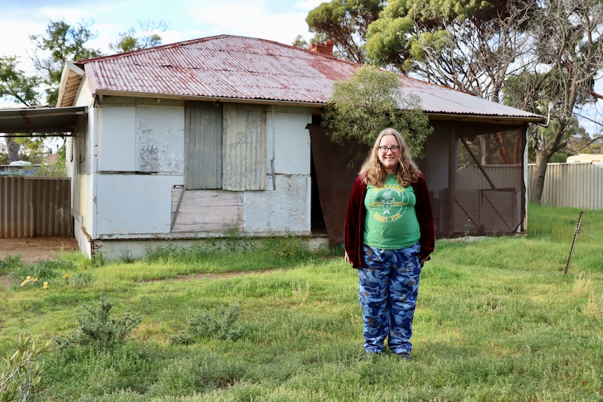 woman standing in front of an old tin house