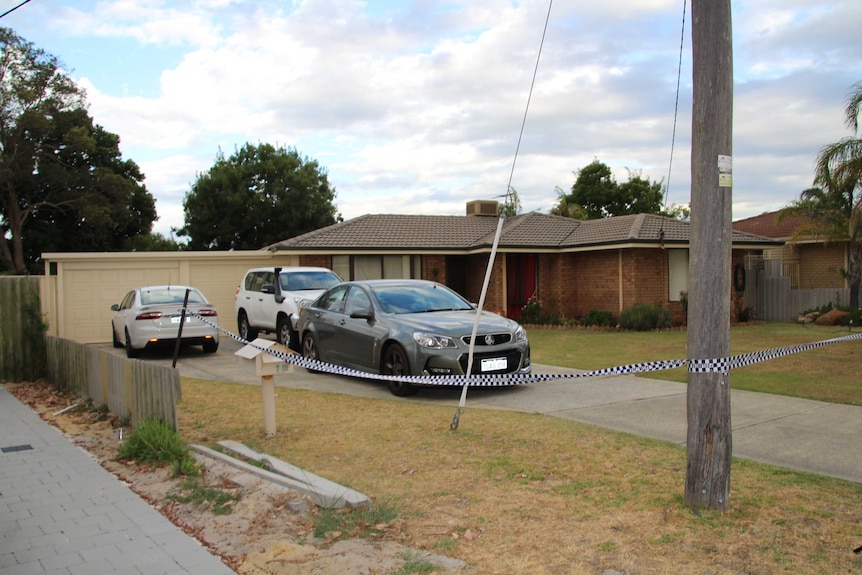 Police tape and cars outside a suburban house.