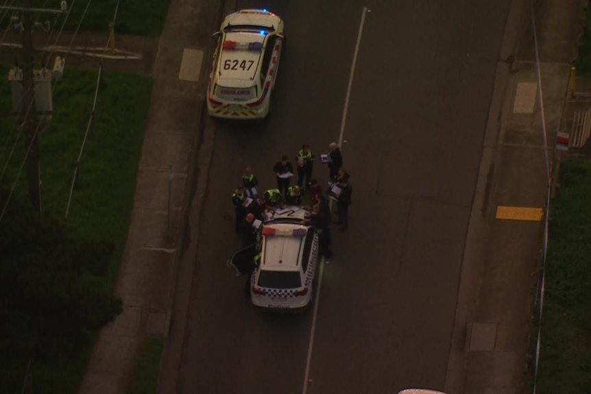 An aerial shot of police officers huddled around a vehicle