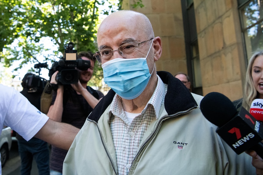 a man wearing a mask and glasses surrounded by cameras