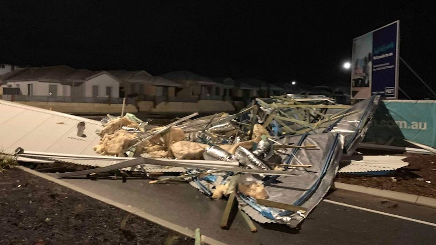 The mangled roof of a house lies on a road with houses in the background.