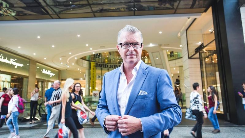 A man wearing suit in front af a store