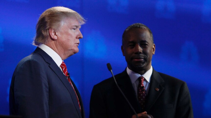 Businessman Donald Trump (L) talks with Dr. Ben Carson (R) during a commercial break at the Republican presidential debate