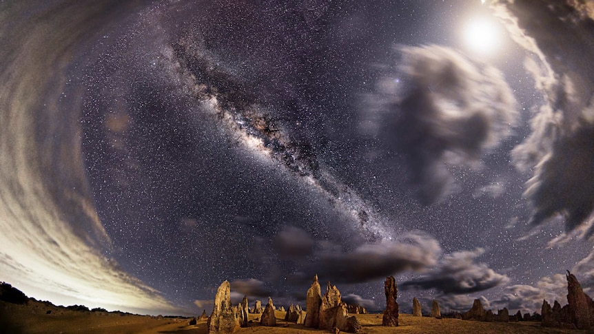 A moon glows in a dark sky over the rocky Pinnacles in Western Australia.