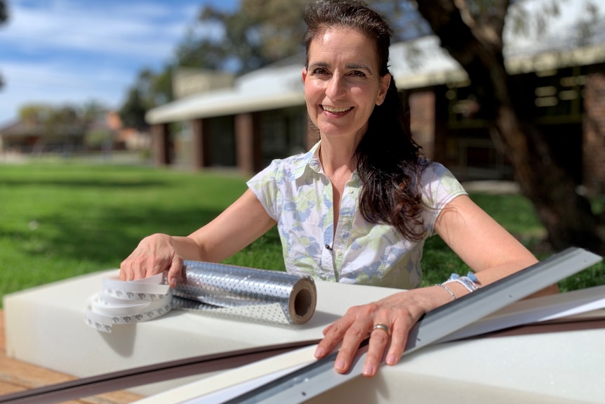 A woman in a white top sits outdoors