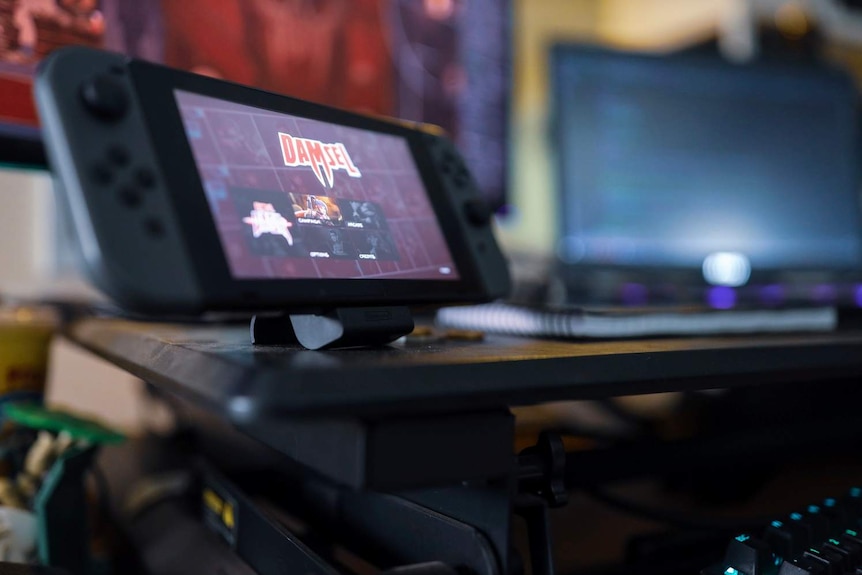 The logo for Screwtape Studios game Damsel is displayed on a Nintendo Switch, with a desk in the background