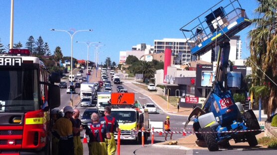 Fire fighters stand near collapsed cherry picker