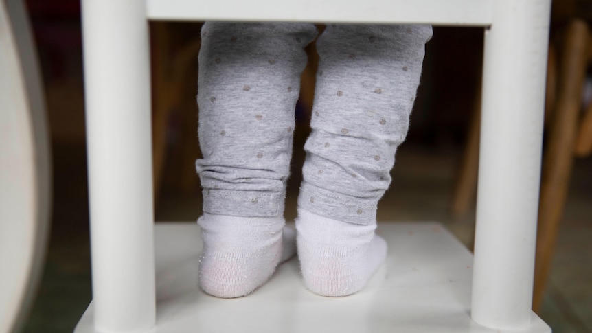 A close-up of child's feet on the stool.