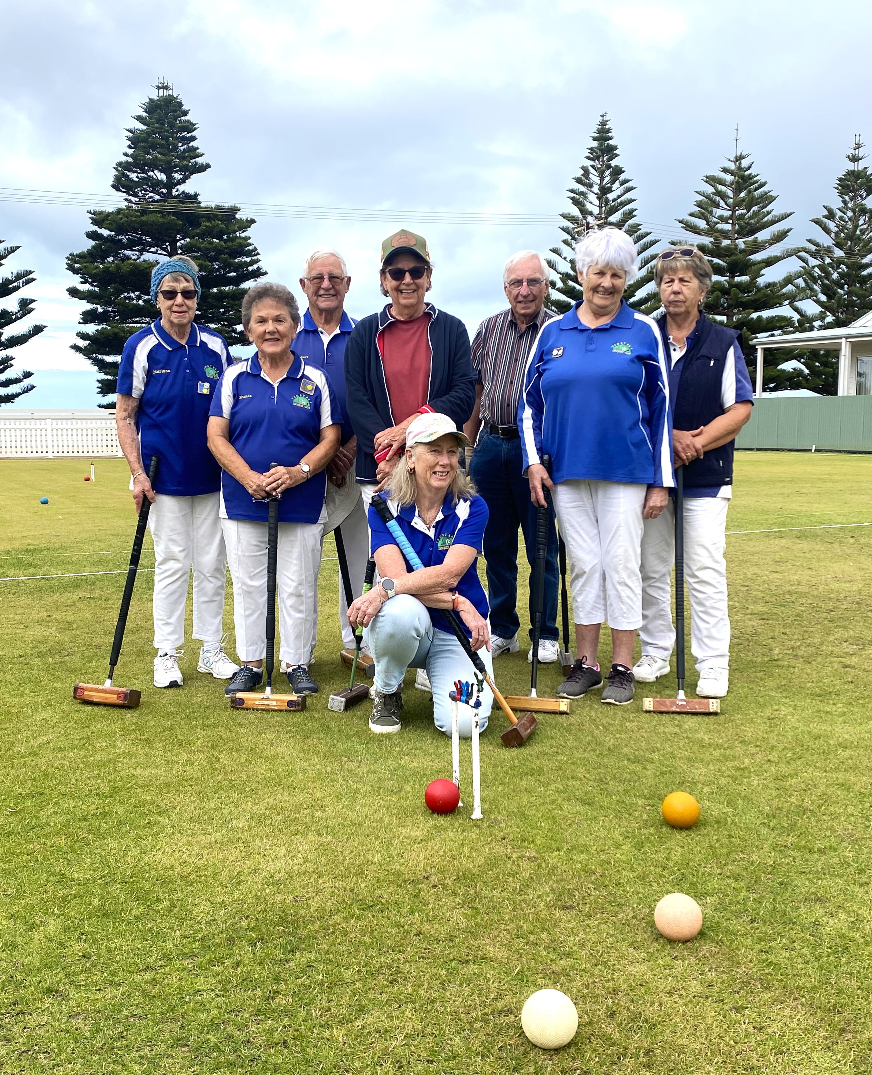 foto de equipe de pessoas agrupadas no gramado segurando marretas com um arco e bolas na grama