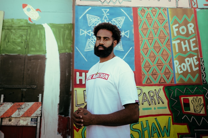 A man stands in front of a painted wall that says 'Afrika'.