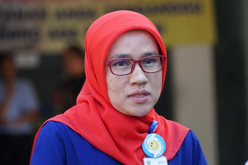 Indonesian nurse Fatriani pictured in her uniform and a red headscarf.