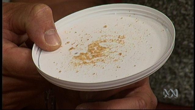 Hands hold white dish with powder substance sprinkled on it