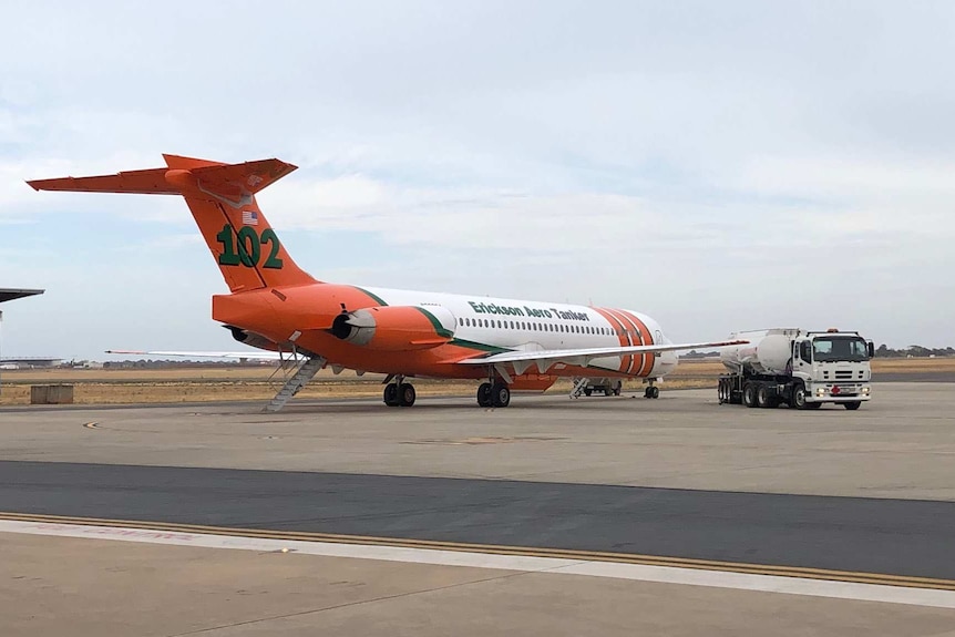 A large orange and white aeroplane on a tarmac