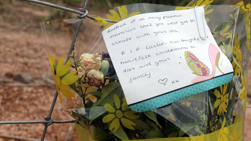 Flowers are left at a fence on a property where police are searching for the remains of Darwin mother Carlie Sinclair