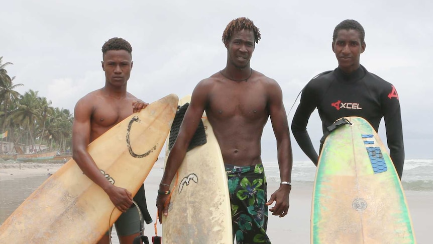 Alphonse Coulibaly (centre) and Souleymane Sidibe (right) stand on the beach with a third man and their surfboards