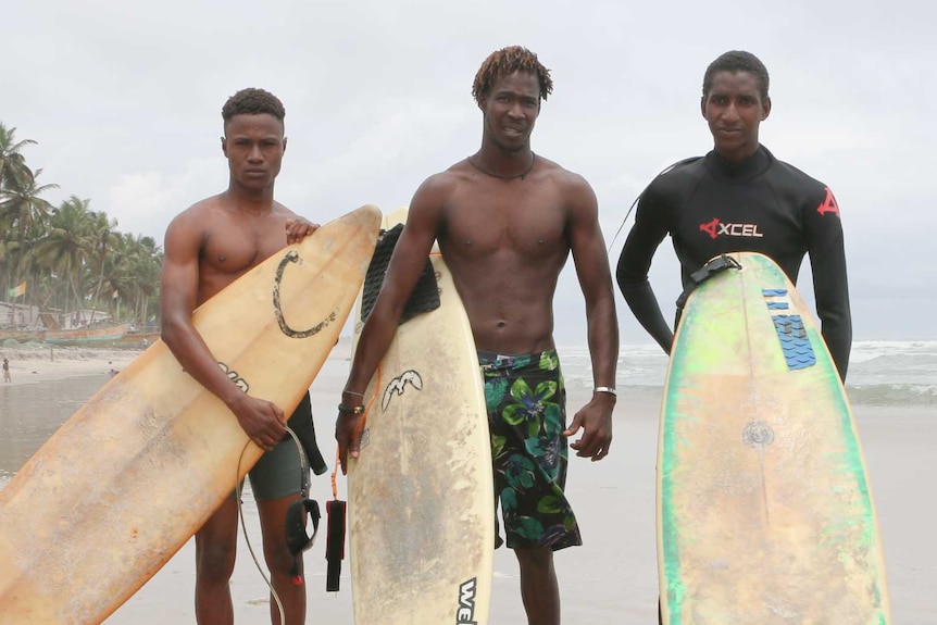 Alphonse Coulibaly (centre) and Souleymane Sidibe (right) stand on the beach with a third man and their surfboards