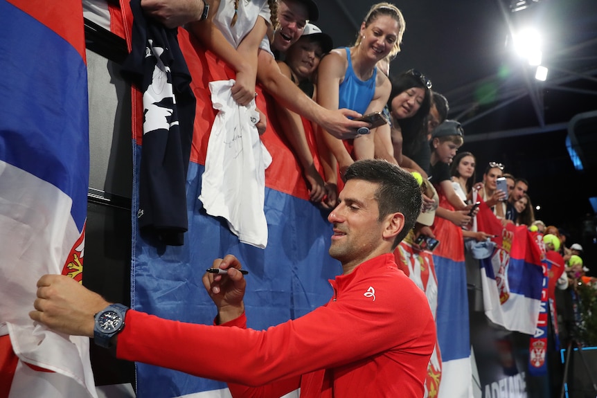 Novak Djokovic autographs a Serbian flag.