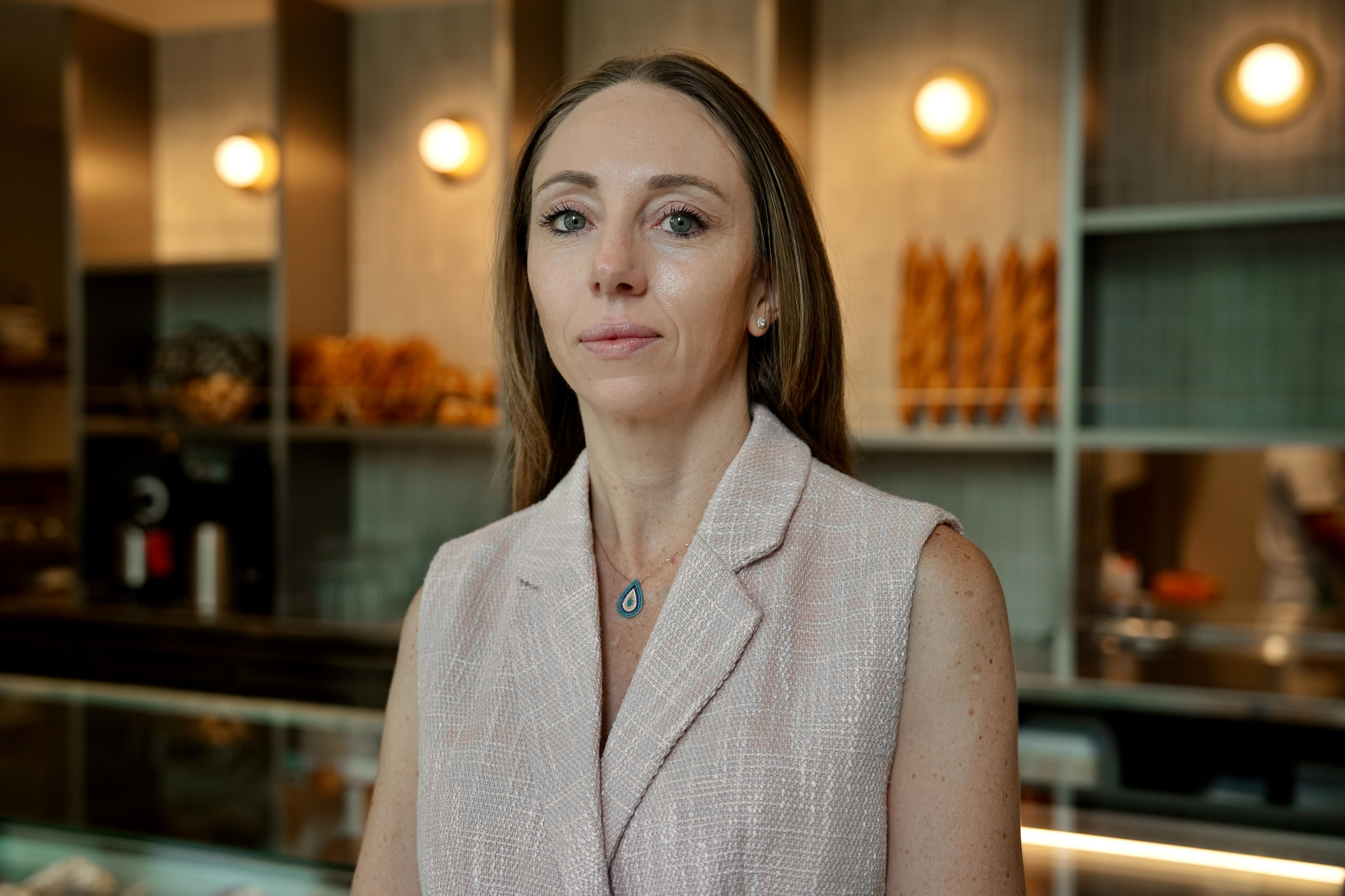 Woman with long hair looks at camera inside her bakery.
