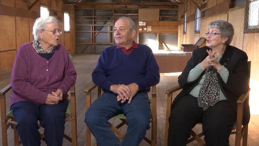 Two elderly women and an elderly man sit in conversation