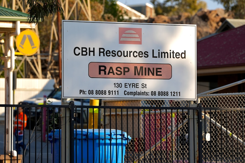A sign reading CBH Resouces Limited Rasp Mine with mine workers standing in the background
