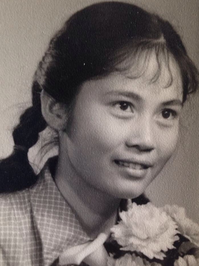 A black and white photo of Helen Zhang holding a flower.