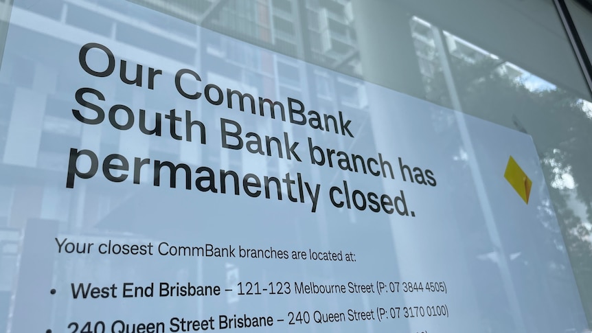 A sign in a window saying a bank branch has closed