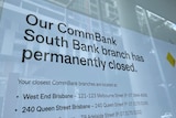 A sign in a window saying a bank branch has closed