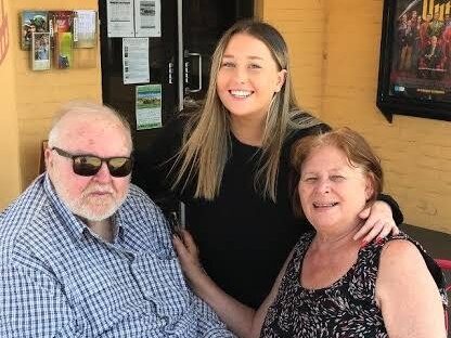 A young woman smiling with her grandparents outside a cinema