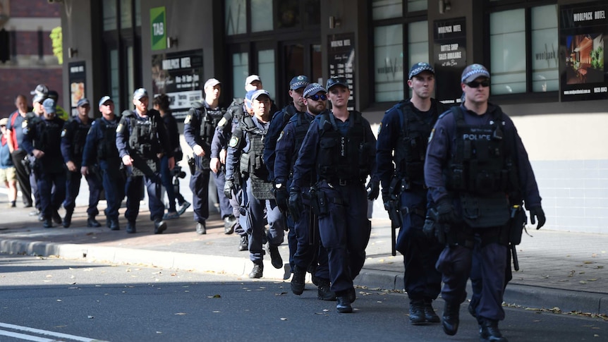 A group of heavily equipped police make their way down a street in Parramatta.