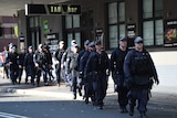 A group of heavily equipped police make their way down a street in Parramatta.