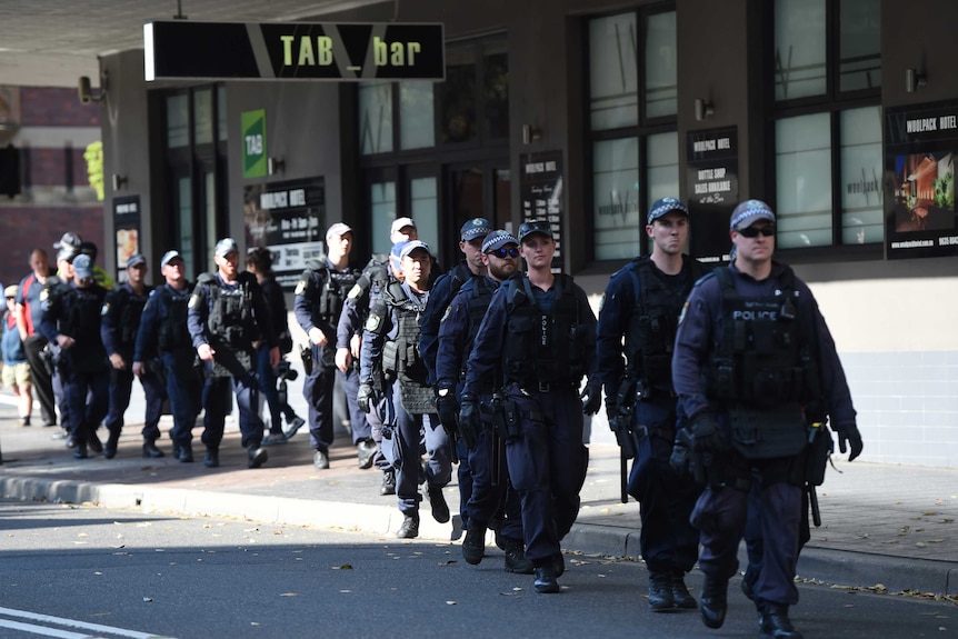 A group of heavily equipped police make their way down a street in Parramatta.