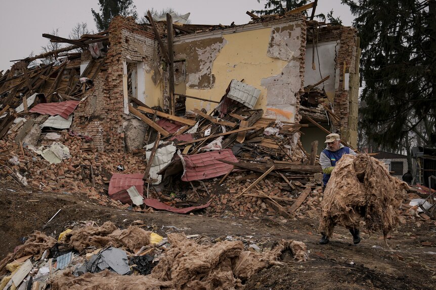 A man removes debris from buildings destroyed during fighting between Russian and Ukrainian forces.