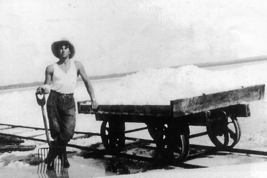 Salt miner Len Synnot standing next to a salt trolley on Pink Lake in 1937.