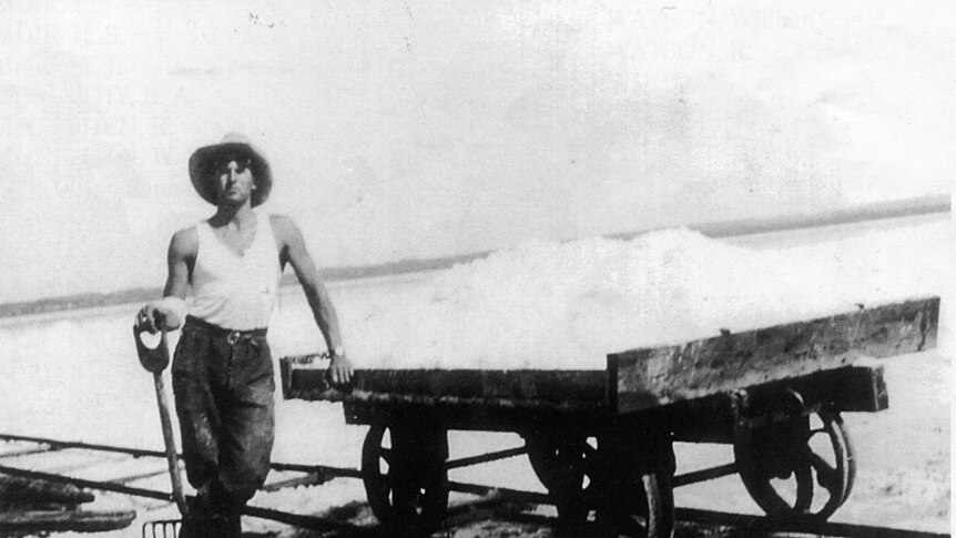 Salt miner Len Synnot standing next to a salt trolley on Pink Lake in 1937.