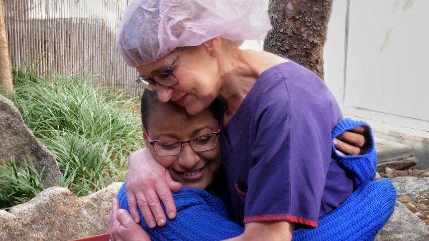 Patient Hare Haro hugs Tracey Foster outside in a garden at Cabrini Hospital.