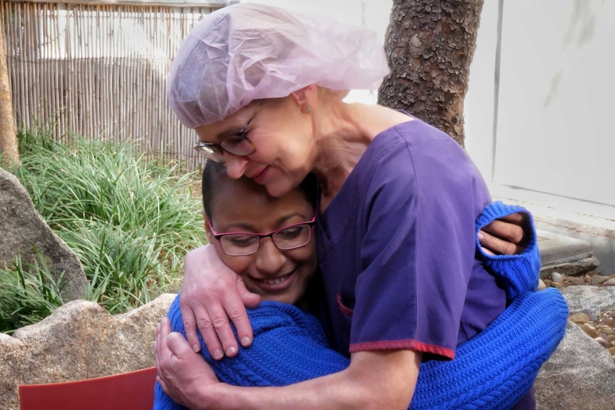 Patient Hare Haro hugs Tracey Foster outside in a garden at Cabrini Hospital.