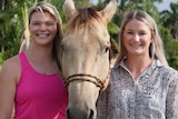 Two women standing either side of a horse